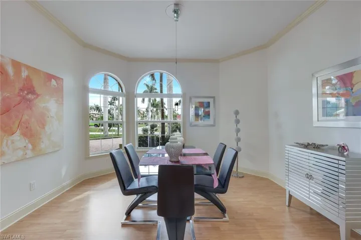Dining space with light hardwood / wood-style flooring and crown molding
