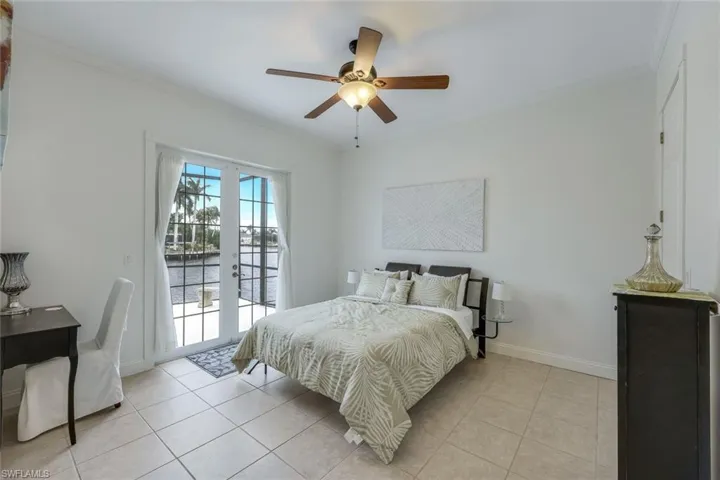 Tiled bedroom featuring ornamental molding, ceiling fan, access to exterior, and french doors