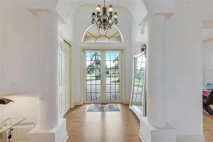 Entrance foyer with french doors, an inviting chandelier, and light wood-type flooring