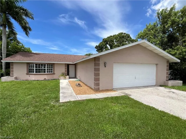 Ranch-style home featuring a garage and a front lawn