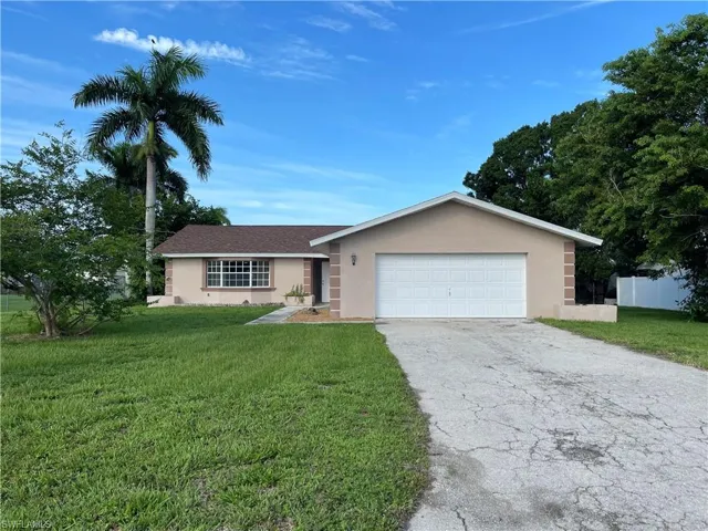 Single story home with a garage and a front lawn