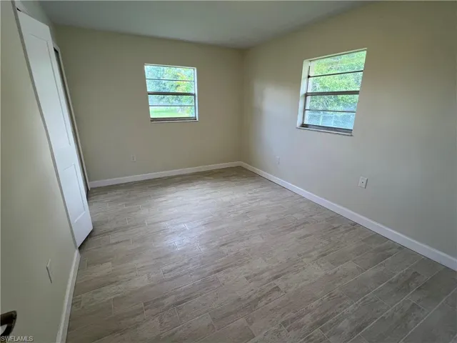 Empty room with vaulted ceiling and hardwood / wood-style floors
