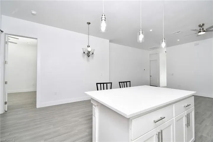 Kitchen with ceiling fan, white cabinets, and pendant lighting