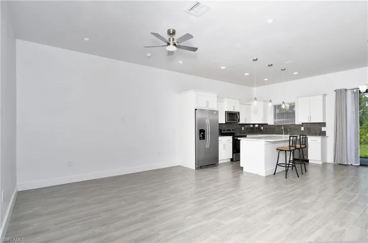 Kitchen featuring stainless steel appliances, open floor plan, hanging light fixtures, a breakfast bar, and a kitchen island
