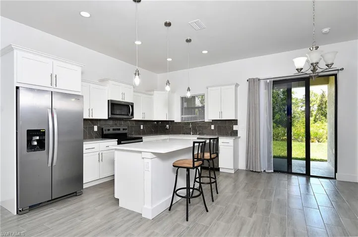 Kitchen with stainless steel appliances, white cabinetry, a kitchen breakfast bar, a kitchen island, and decorative backsplash