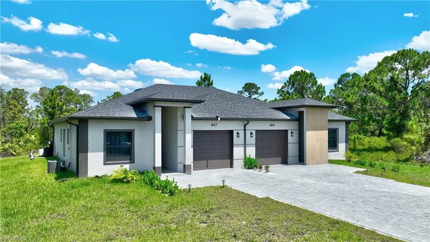 View of front of property with an attached garage, roof with shingles, a front lawn, and decorative driveway