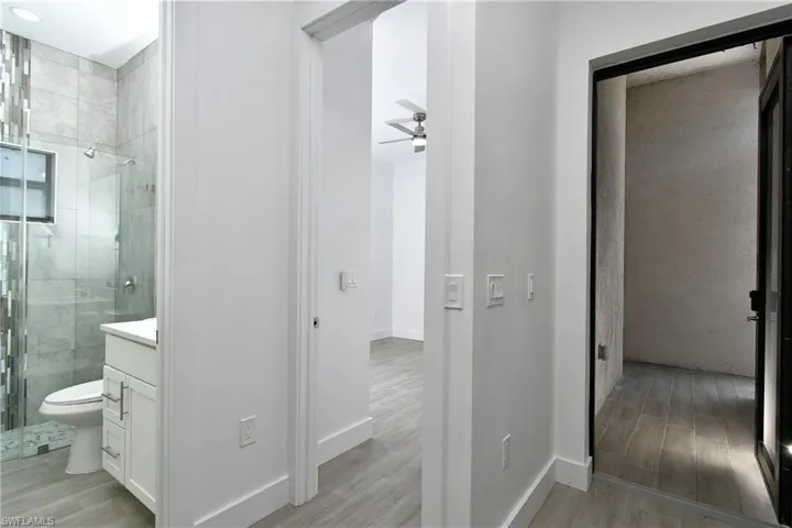 Bathroom with a shower stall, vanity, light wood-type flooring, and a ceiling fan