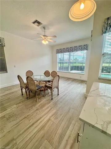 Dining area with a textured ceiling, light wood finished floors, and a ceiling fan