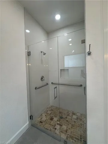 Bathroom with a stall shower, recessed lighting, and a textured wall