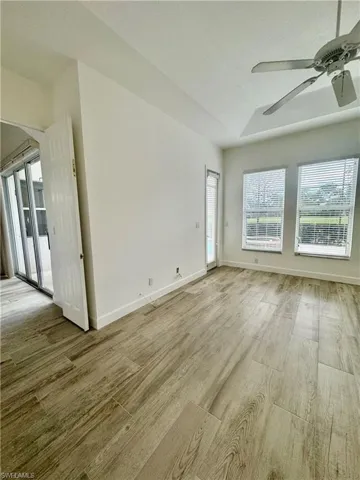 Unfurnished living room featuring a ceiling fan, light wood finished floors, a raised ceiling, and arched walkways