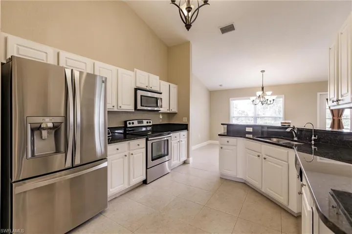Kitchen featuring a notable chandelier, decorative light fixtures, white cabinets, and stainless steel appliances