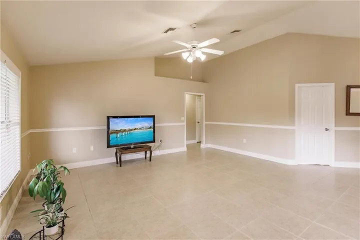 Living area featuring ceiling fan, lofted ceiling, and light tile patterned floors