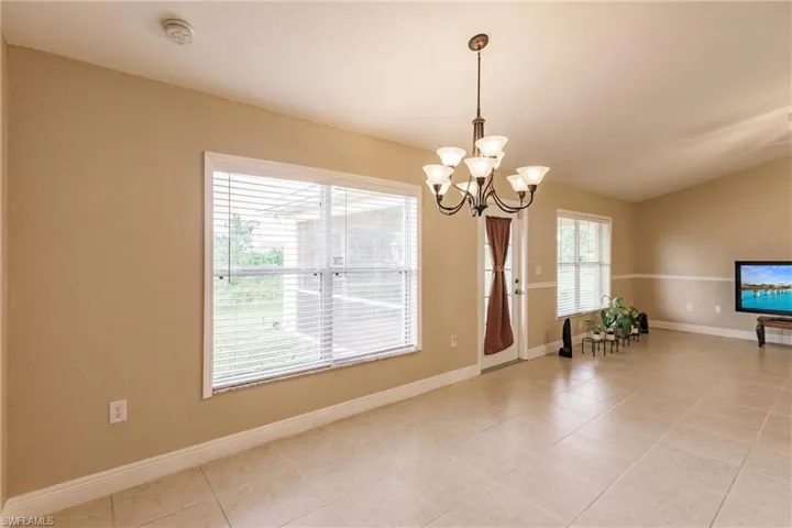 Tiled empty room featuring a notable chandelier