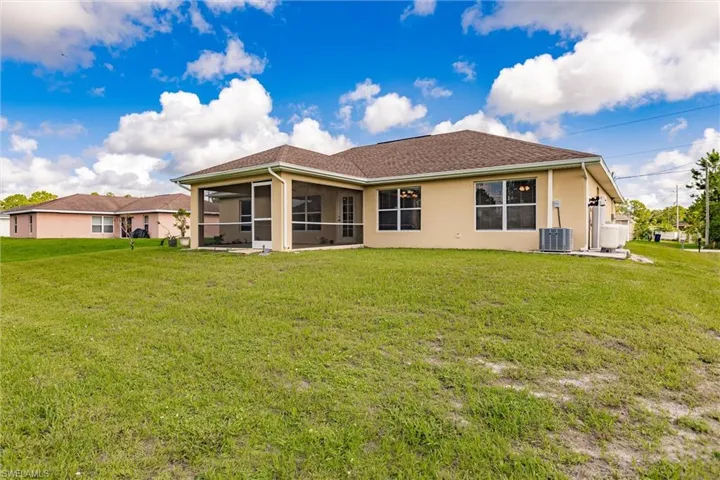Back of house featuring a lawn, central AC, and a sunroom