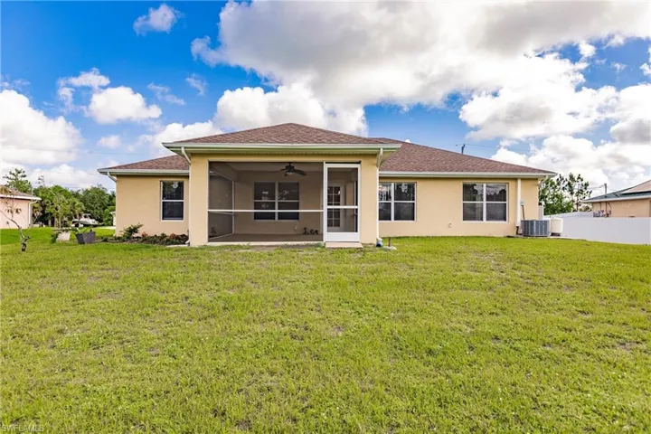 Back of property with central AC, a lawn, and ceiling fan