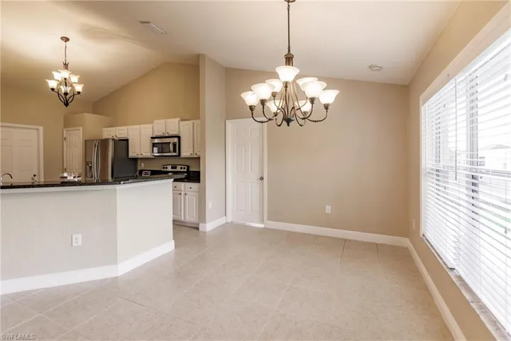 Kitchen with light tile patterned flooring, pendant lighting, a notable chandelier, and appliances with stainless steel finishes