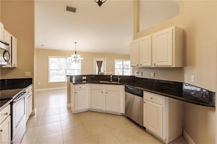 Kitchen with plenty of natural light, white cabinetry, pendant lighting, and stainless steel appliances