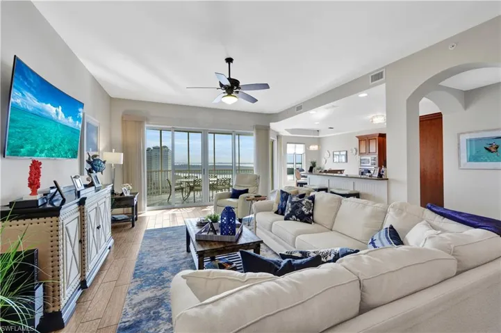 Living area with wood finish floors, a ceiling fan, and arched walkways