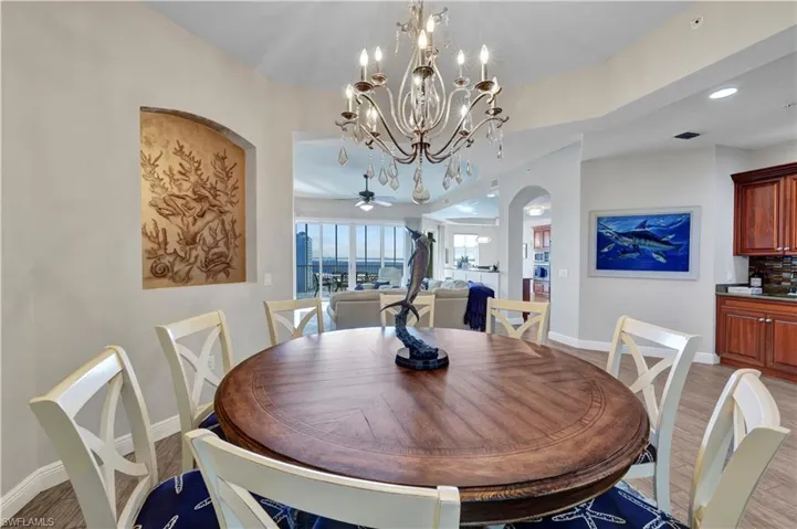 Dining room with arched walkways, a ceiling fan, hanging lights, and light wood-type flooring
