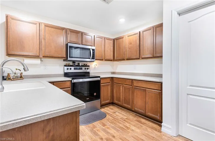 Kitchen with appliances with stainless steel finishes, a sink, light countertops, light wood-style floors, and recessed lighting
