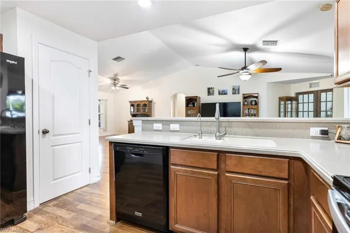 Kitchen with brown cabinets, ceiling fan, a sink, light wood-type flooring, and black appliances