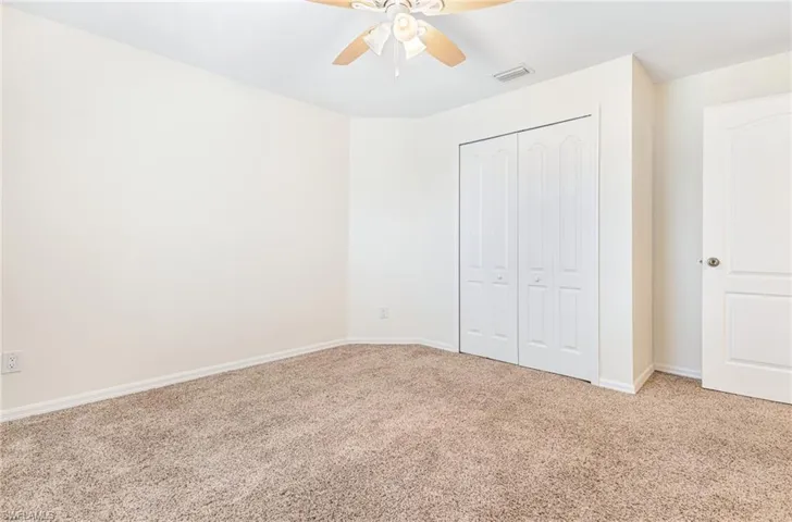 Unfurnished bedroom featuring baseboards, light carpet, a closet, and visible vents