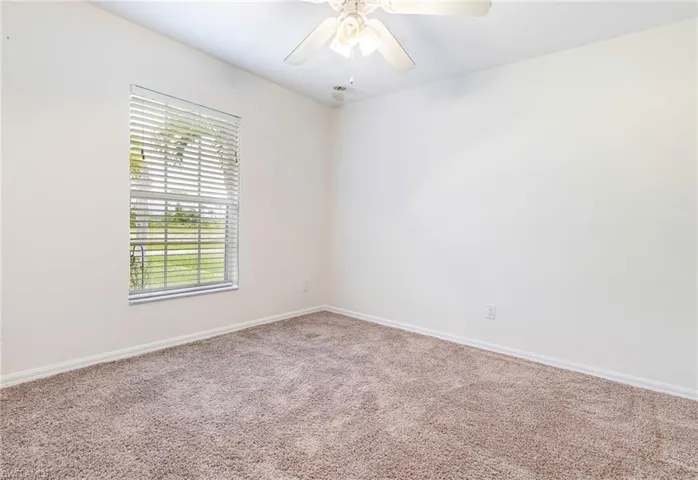 Unfurnished room featuring carpet floors, baseboards, and ceiling fan