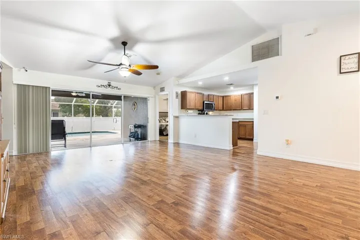 Unfurnished living room featuring high vaulted ceiling, light wood-style flooring, a ceiling fan, baseboards, and visible vents