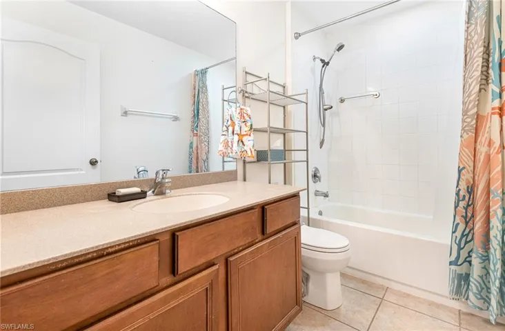 Bathroom with vanity, tile patterned floors, toilet, and shower / bathtub combination with curtain