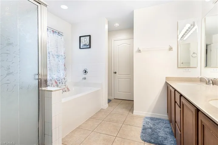 Full bath with a sink, tile patterned flooring, a shower stall, and a bath