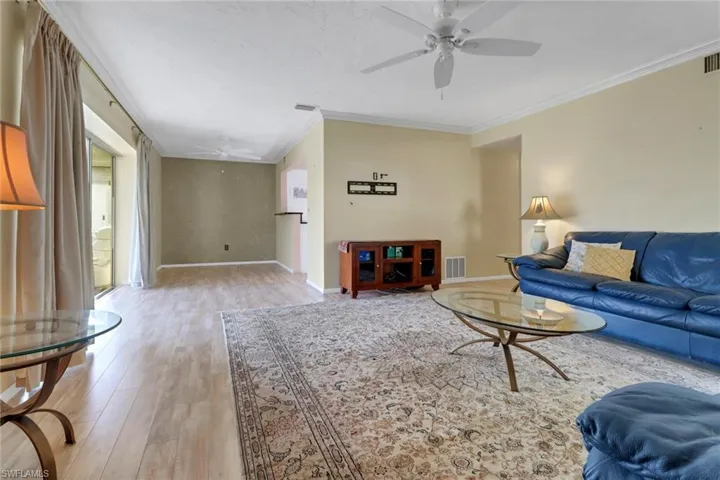 Living room with ceiling fan, crown molding, and light wood-style flooring