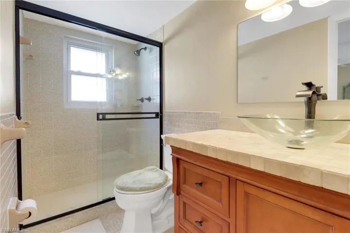 Bathroom featuring tile walls, vanity, and a stall shower