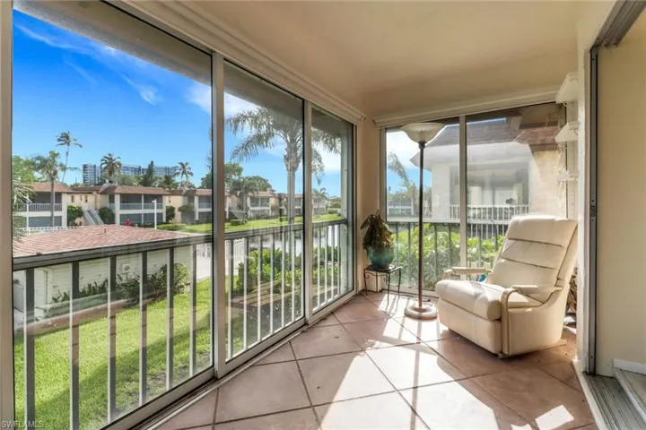 Sunroom featuring a water view, tile patterned flooring, and a residential view