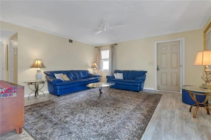 Living room featuring ceiling fan, wood finished floors, and crown molding