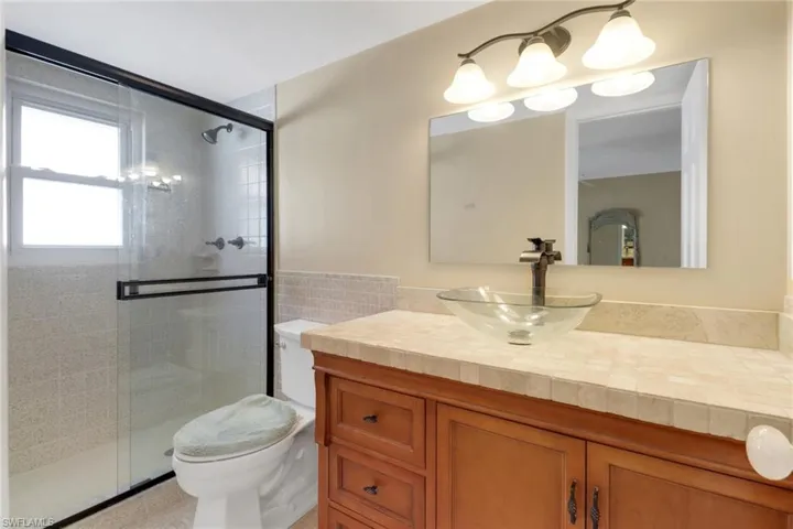 Bathroom with vanity, a stall shower, and tile walls