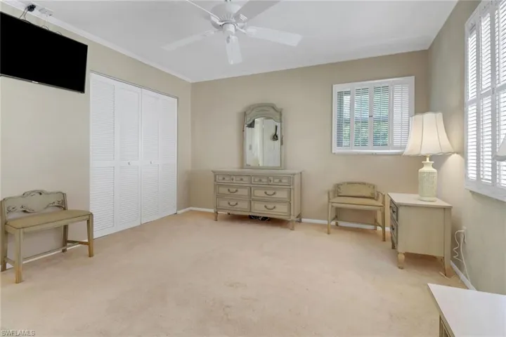Sitting room featuring healthy amount of natural light, light carpet, a ceiling fan, and ornamental molding