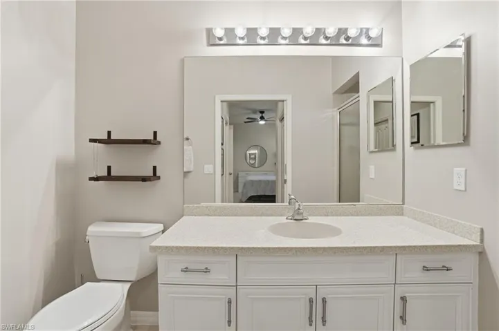 Full bathroom with vanity, connected bathroom, a shower with door, and ceiling fan
