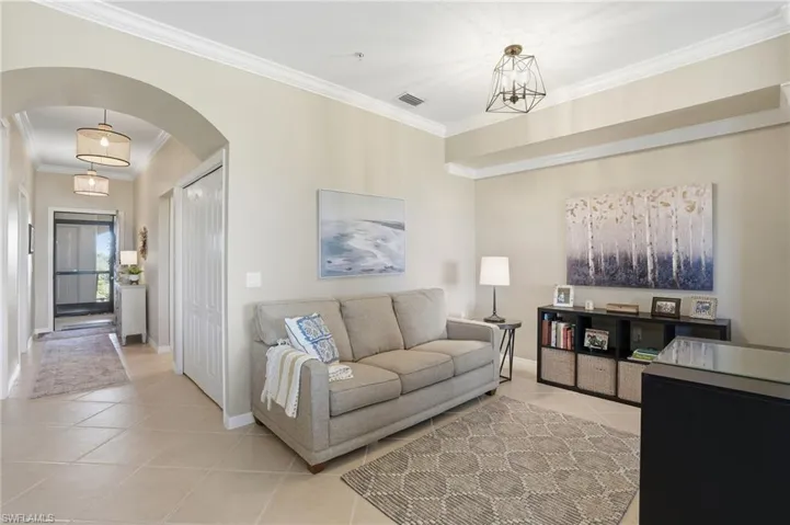 Living room with arched walkways, ornamental molding, and light tile patterned flooring
