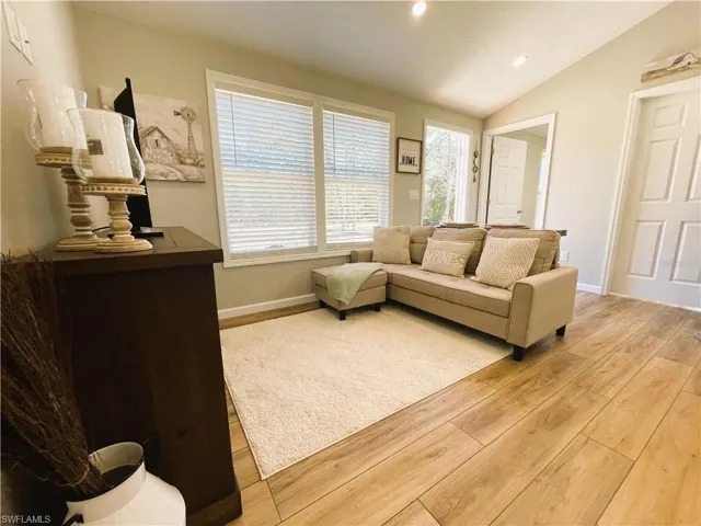 Living room with light hardwood / wood-style flooring and lofted ceiling