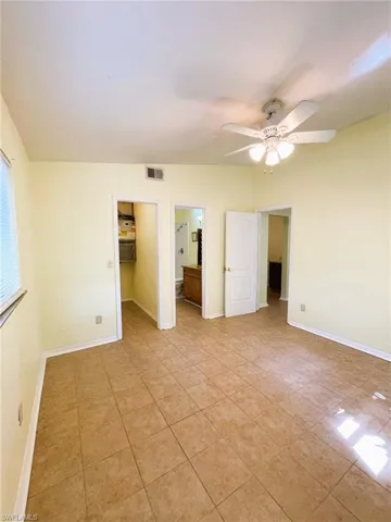 Unfurnished bedroom with a walk in closet, a ceiling fan, connected bathroom, and light tile patterned floors