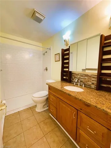 Full bathroom featuring vanity, light tile patterned floors, tasteful backsplash, and bathing tub / shower combination