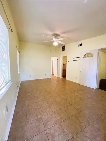 Tiled spare room featuring a ceiling fan and baseboards