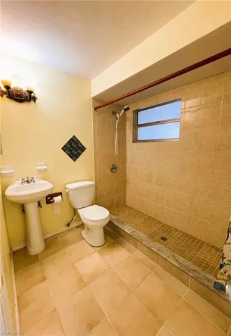 Bathroom with tiled shower and tile patterned floors