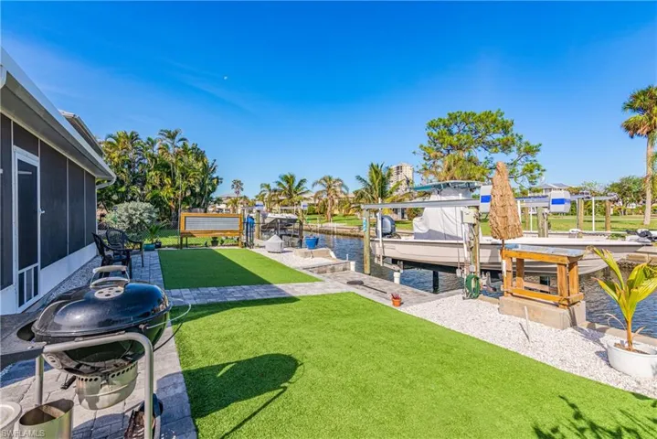 View of yard featuring a water view, a sunroom, and a dock