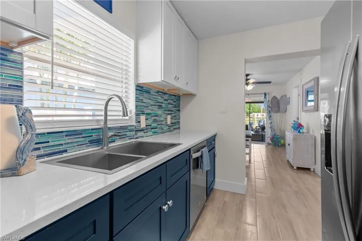 Kitchen with sink, ceiling fan, blue cabinetry, appliances with stainless steel finishes, and white cabinetry
