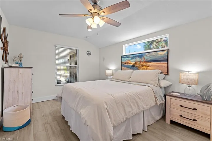 Bedroom with ceiling fan, light wood-type flooring, and vaulted ceiling
