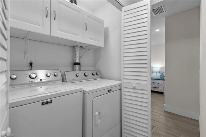 Laundry area featuring washer and dryer, light hardwood / wood-style floors, and cabinets