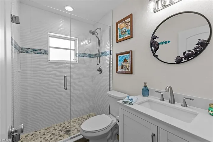 Bathroom featuring a shower with door, vanity, and toilet