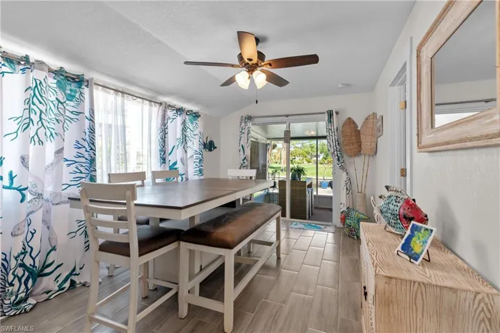 Dining area with lofted ceiling, ceiling fan, light wood-type flooring, and a textured ceiling