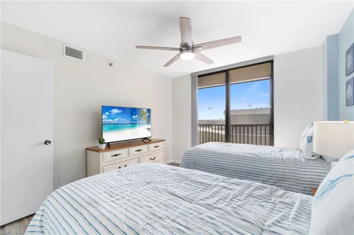 Bedroom with access to exterior, a ceiling fan, floor to ceiling windows, and wood finished floors